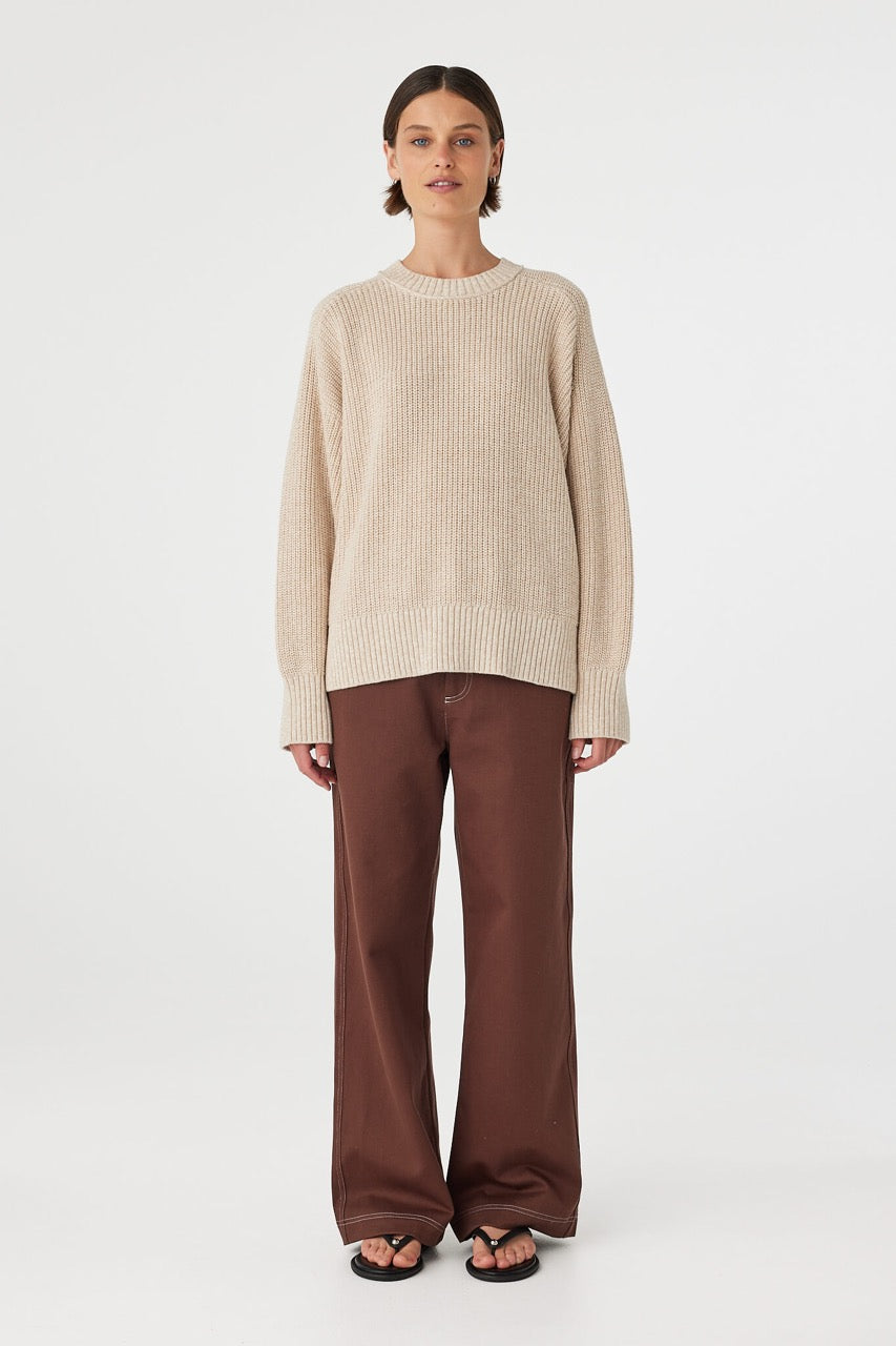 Full body front view of oversized cream sweater paired with brown pants