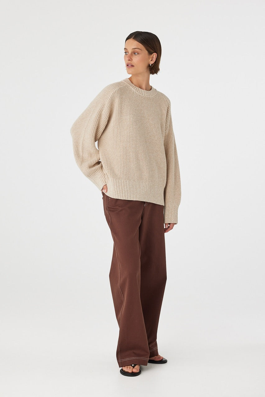 Angled front view of cream sweater showing oversized silhouette