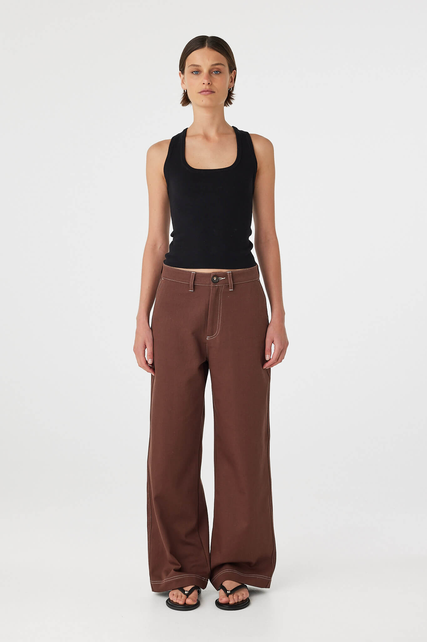 Full body front view of Sable Top black, racerback knit tank styled with brown pants.