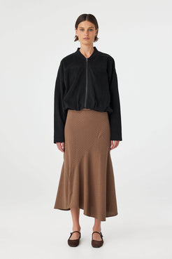 Model wearing Alessia Skirt in choc polka dot, fitted waist cotton A-line skirt with asymmetrical hem, front view.