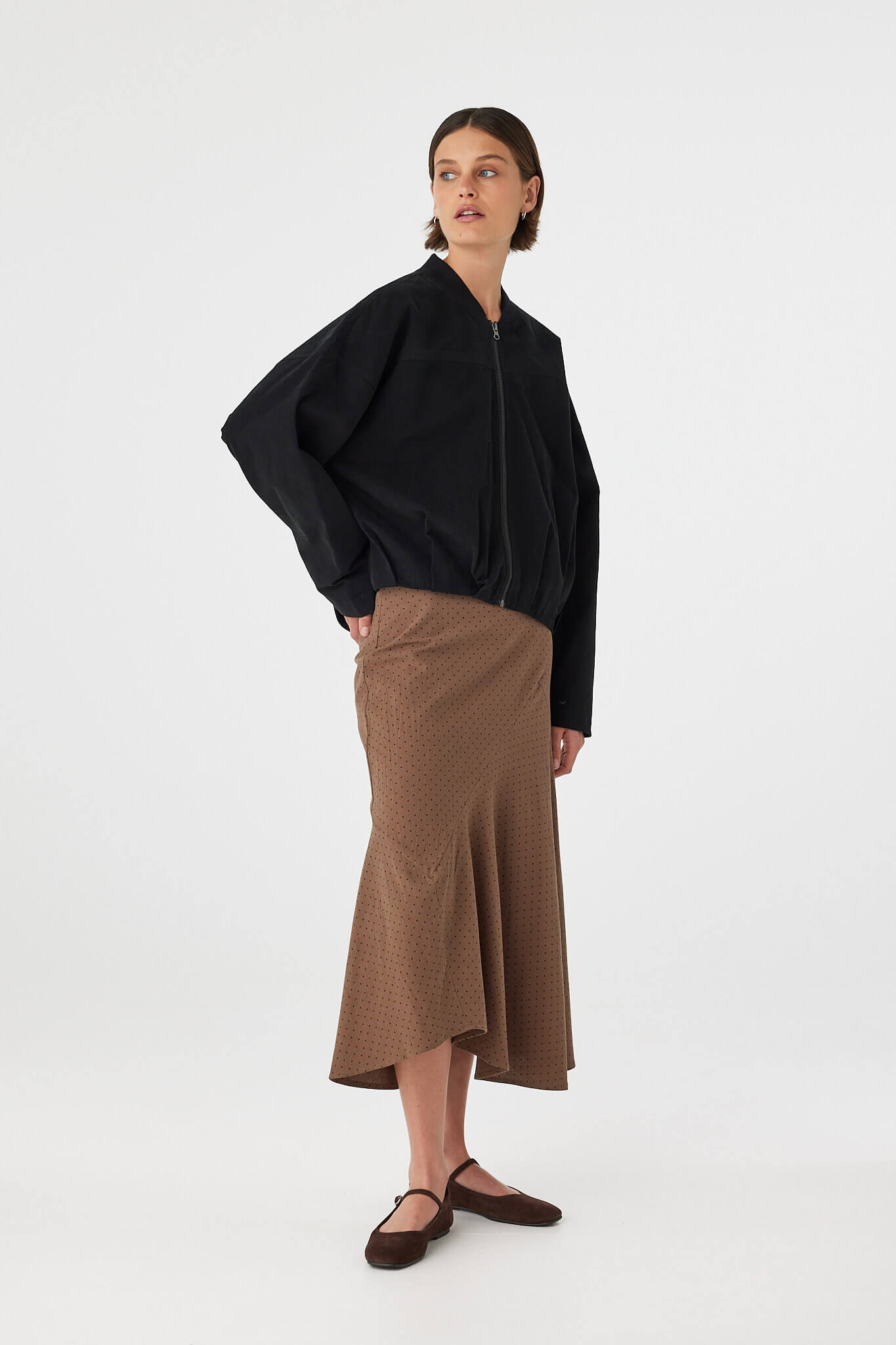 Three-quarter view of Alessia Skirt in choc polka dot, fitted waist and swingy asymmetrical bias-cut hem.