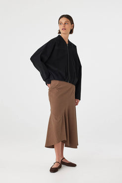 Three-quarter view of Alessia Skirt in choc polka dot, fitted waist and swingy asymmetrical bias-cut hem.