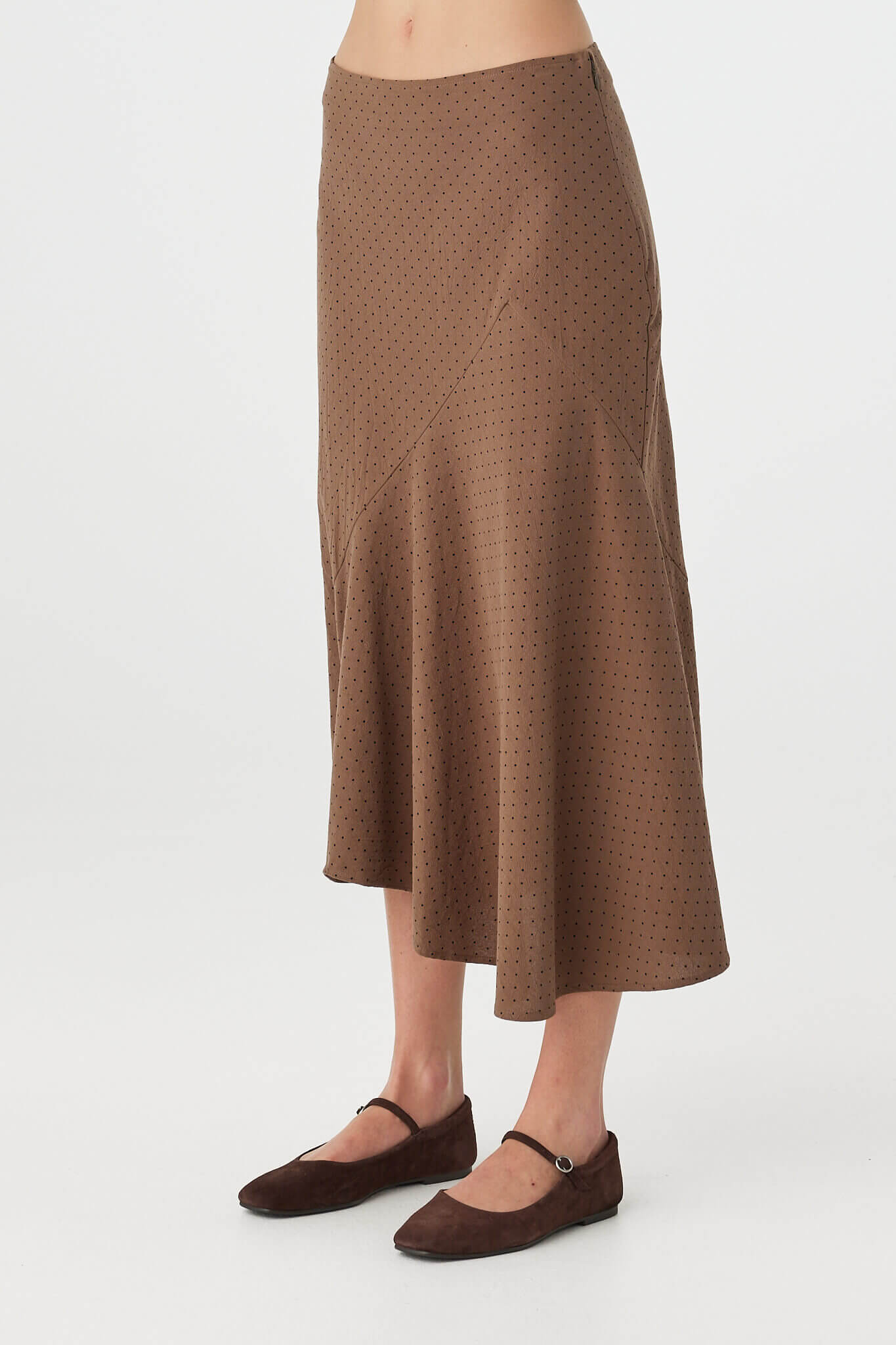 Side view of Alessia Skirt in choc polka dot, fitted waist with side seam zip and A-line fall through the skirt.
