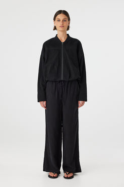 Model wearing Rae Pant in black, straight-leg cupro–rayon pants with elastic drawcord waistband, full front view.