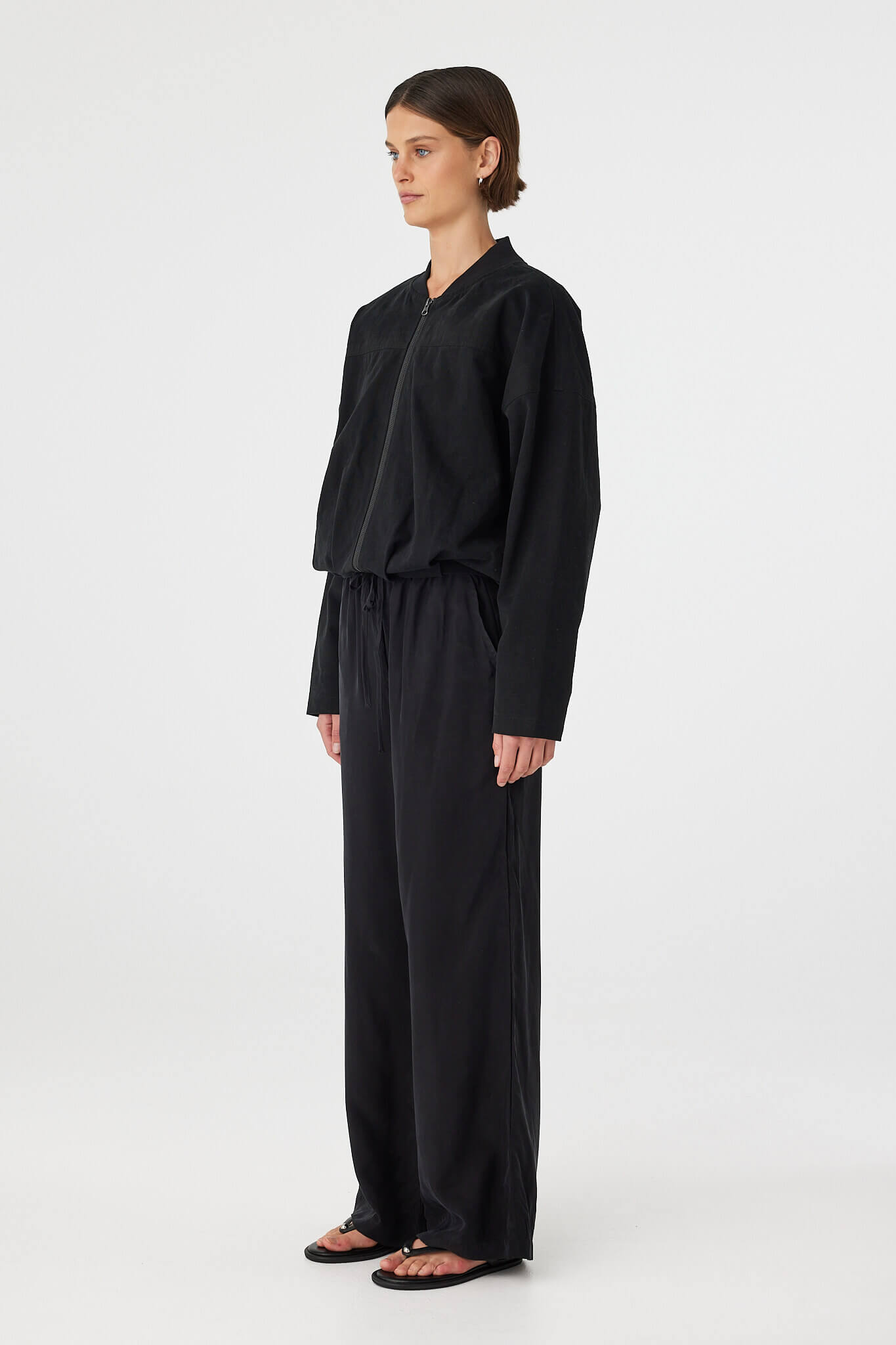 Side view of black bomber jacket with relaxed silhouette