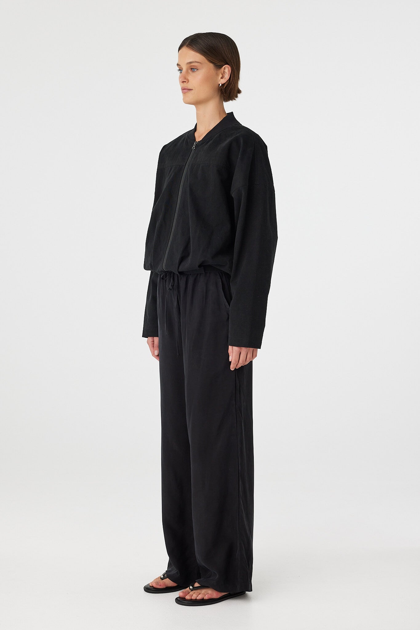 Side view of Rae Pant in black, fluid drape through the straight leg with elastic drawcord waist.