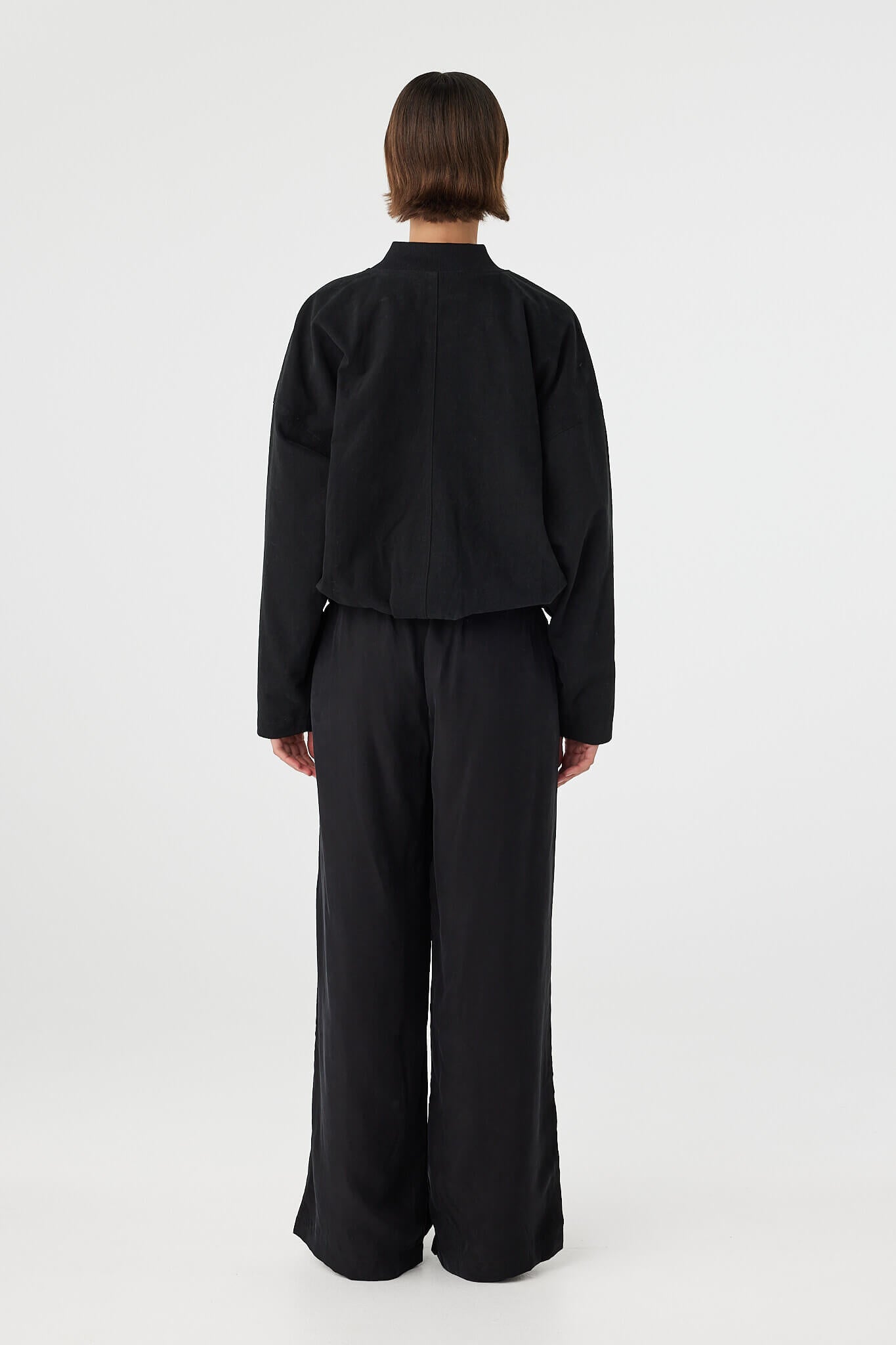 Back view of black bomber jacket with elasticated hem