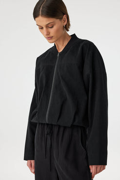 Close-up angled view of black bomber jacket showing relaxed fit