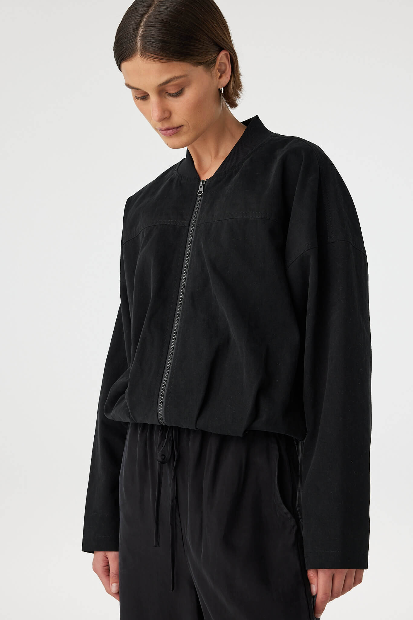 Close-up angled view of black bomber jacket showing relaxed fit
