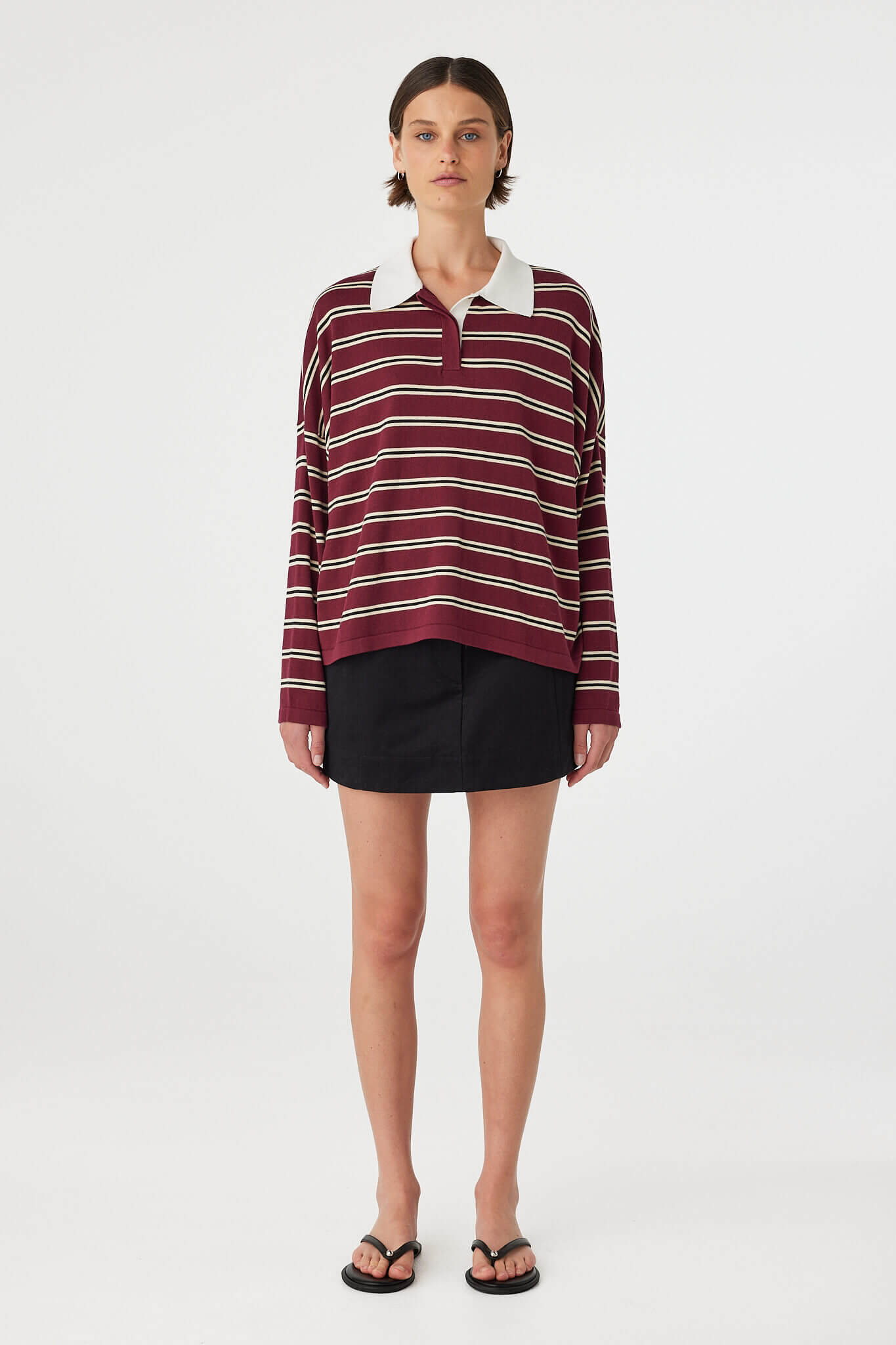 Model wearing Eames Mini Skirt in black, cotton mini skirt with velvet finish and fitted waistband, front view.