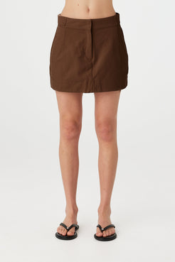Eames mini skirt in espresso worn front on, showcasing the clean waistband, front fly closure and smooth velvet finish