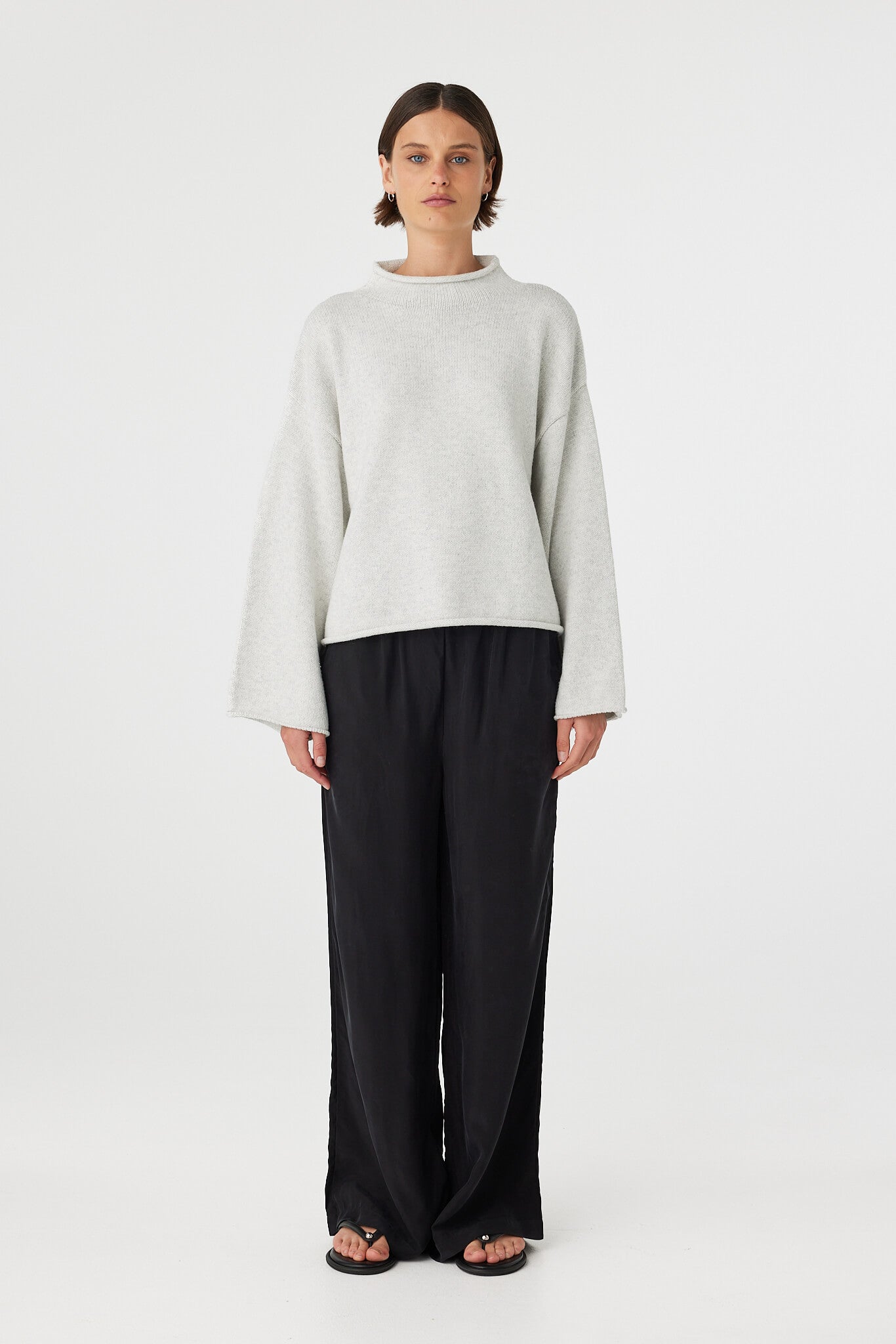 Maeve sweater in snow marle worn front on, featuring a relaxed fit, funnel neckline and cropped length, styled with black wide leg pants
