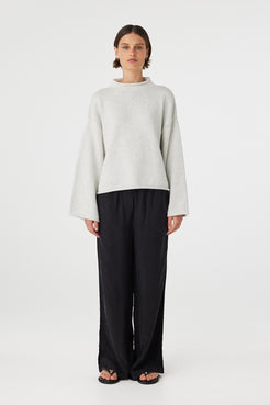 Maeve sweater in snow marle worn front on, featuring a relaxed fit, funnel neckline and cropped length, styled with black wide leg pants