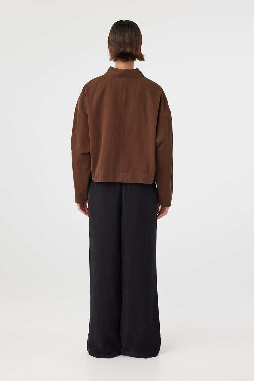 Eames jacket in espresso viewed from back, featuring a clean silhouette with subtle seam detailing and waistband tabs, styled with black pants