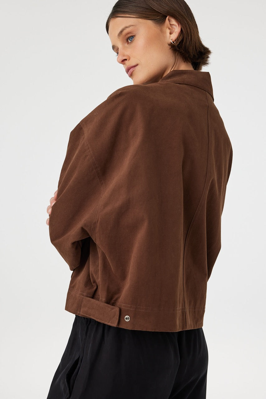 Eames jacket in espresso worn from a back angled view, showing the smooth finish, seam lines and side tab detail at the waistband