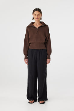 Marley zip sweater in espresso worn front on, showcasing the ribbed knit texture, exaggerated funnel neck collar and 1/4 zip detail, styled with black wide-leg pants and sandals