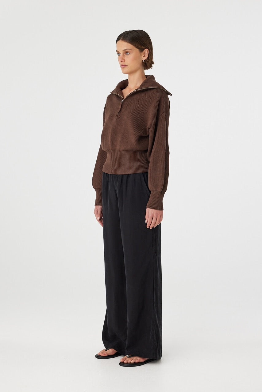 Marely zip sweater in espresso shown in side profile, highlighting the structured collar, relaxed fit and ribbed fabrication, styled with black pants and sandals
