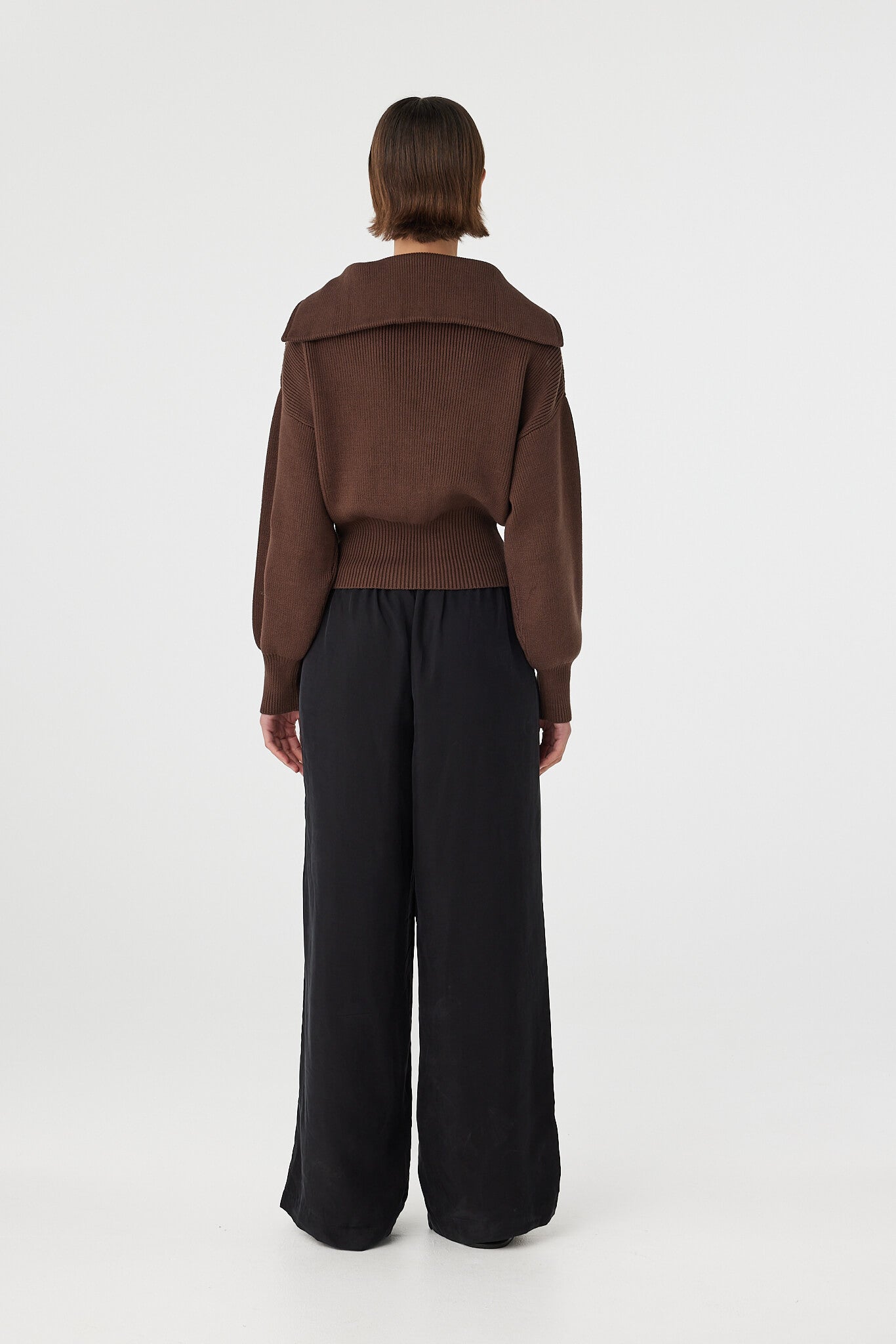 Marley zip sweater in espresso viewed from back, featuring the clean silhouette, ribbed texture and fitted waistband, styled with black pants and sandals