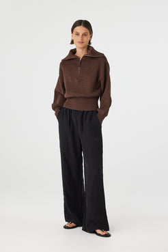 Marley zip sweater in espresso worn at an angle, highlighting the 1/4 zip neckline, funnel collar and soft structure, styled with black pants and sandals