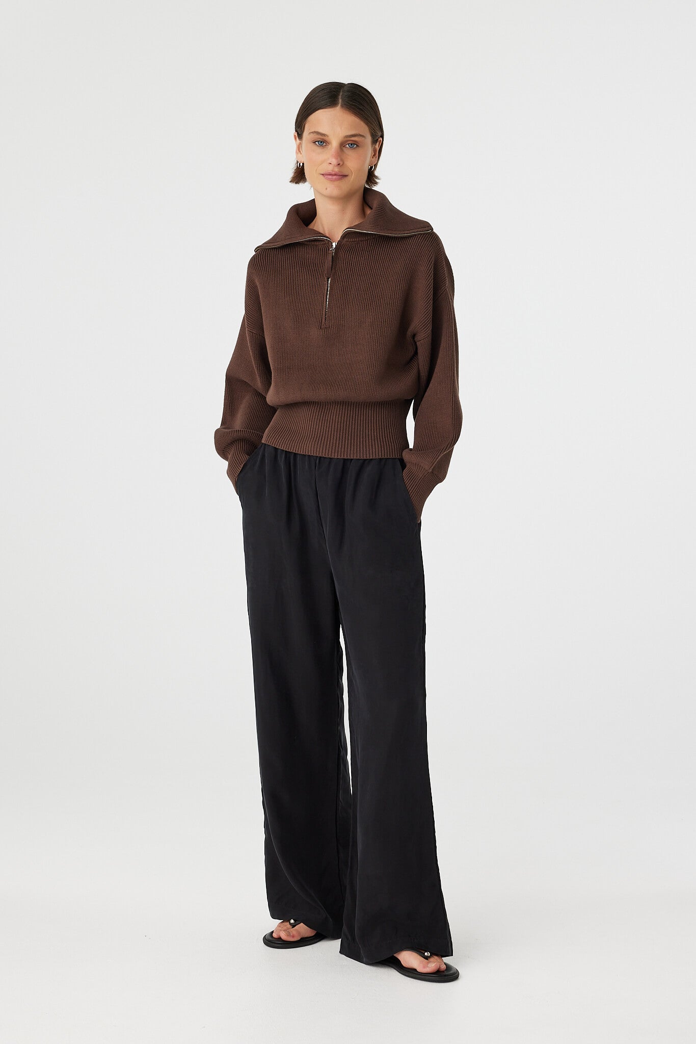 Marley zip sweater in espresso worn at an angle, highlighting the 1/4 zip neckline, funnel collar and soft structure, styled with black pants and sandals