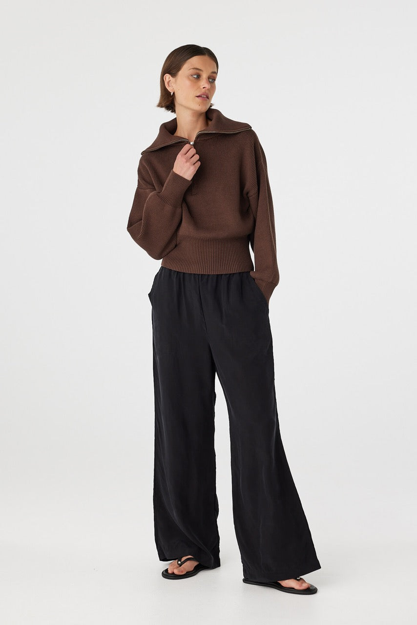Marely zip sweater in espresso worn at an angle with hand at neckline, showcasing the zip detail, ribbed knit and collar shape, styled with black pants and sandals