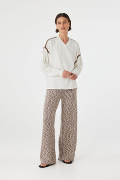Eden long sleeve tee in cream and espresso worn at an angle, showcasing the contrast stripe detail along the shoulder and armhole, paired with relaxed marled pants