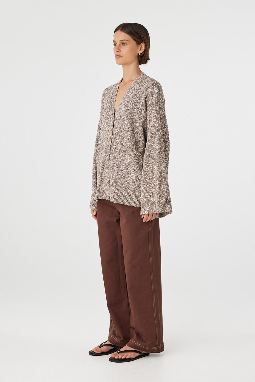 Emmet cardigan in chocolate and cream shown in side profile, featuring the longline silhouette, relaxed fit and textured knit finish, styled with brown pants and sandals