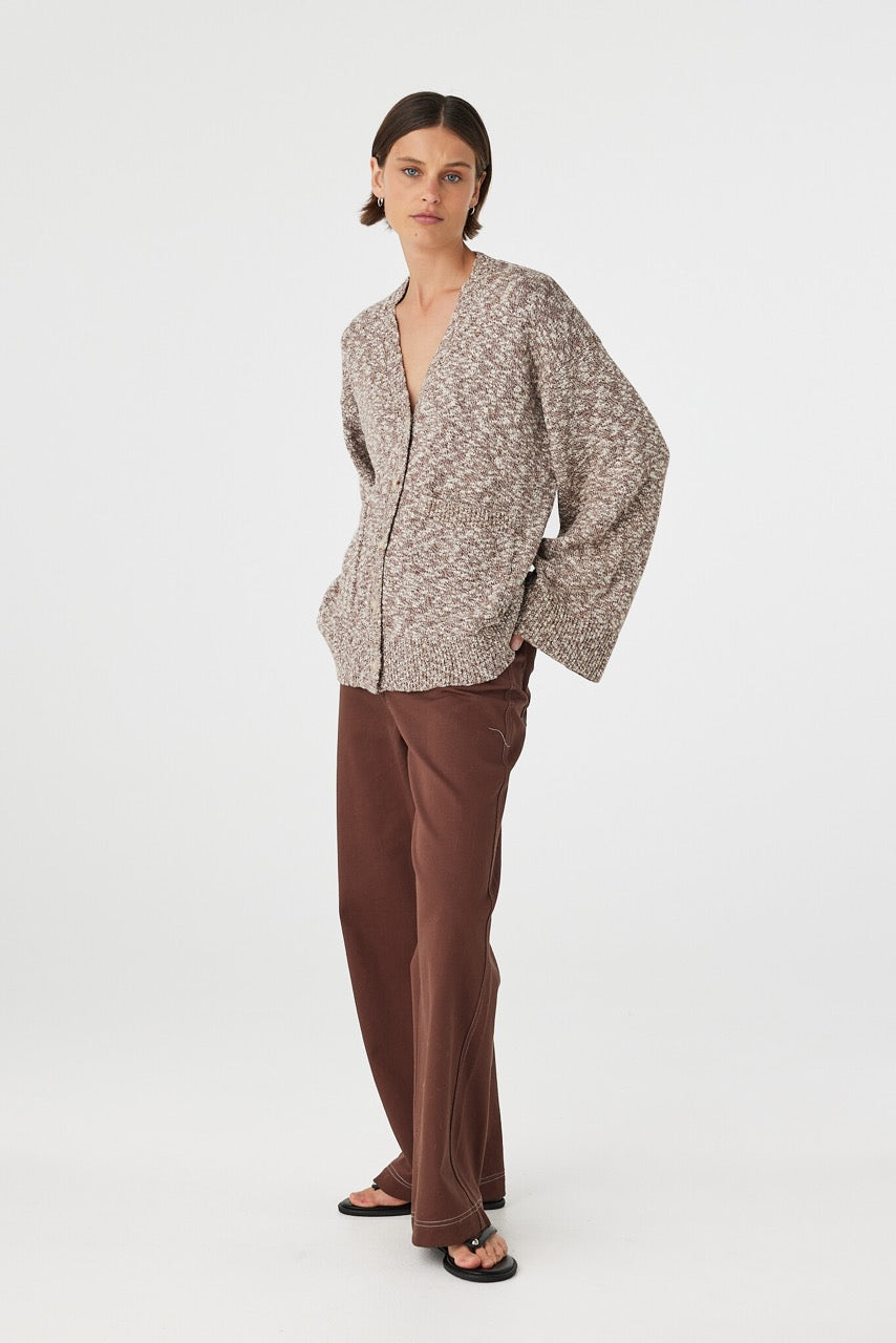 Emmet cardigan in chocolate and cream worn at an angle, highlighting the button front detail, wide sleeves and soft slub knit texture, styled with brown pants and sandals