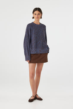Eames mini skirt in espresso styled with a knit sweater at an angle, showing the fit through the hips and hemline
