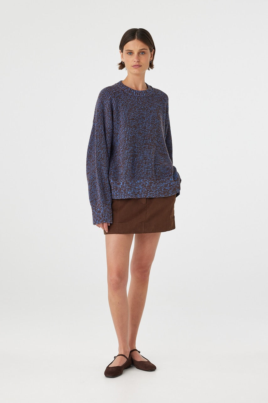 Eames mini skirt in espresso styled with a knit sweater at an angle, showing the fit through the hips and hemline