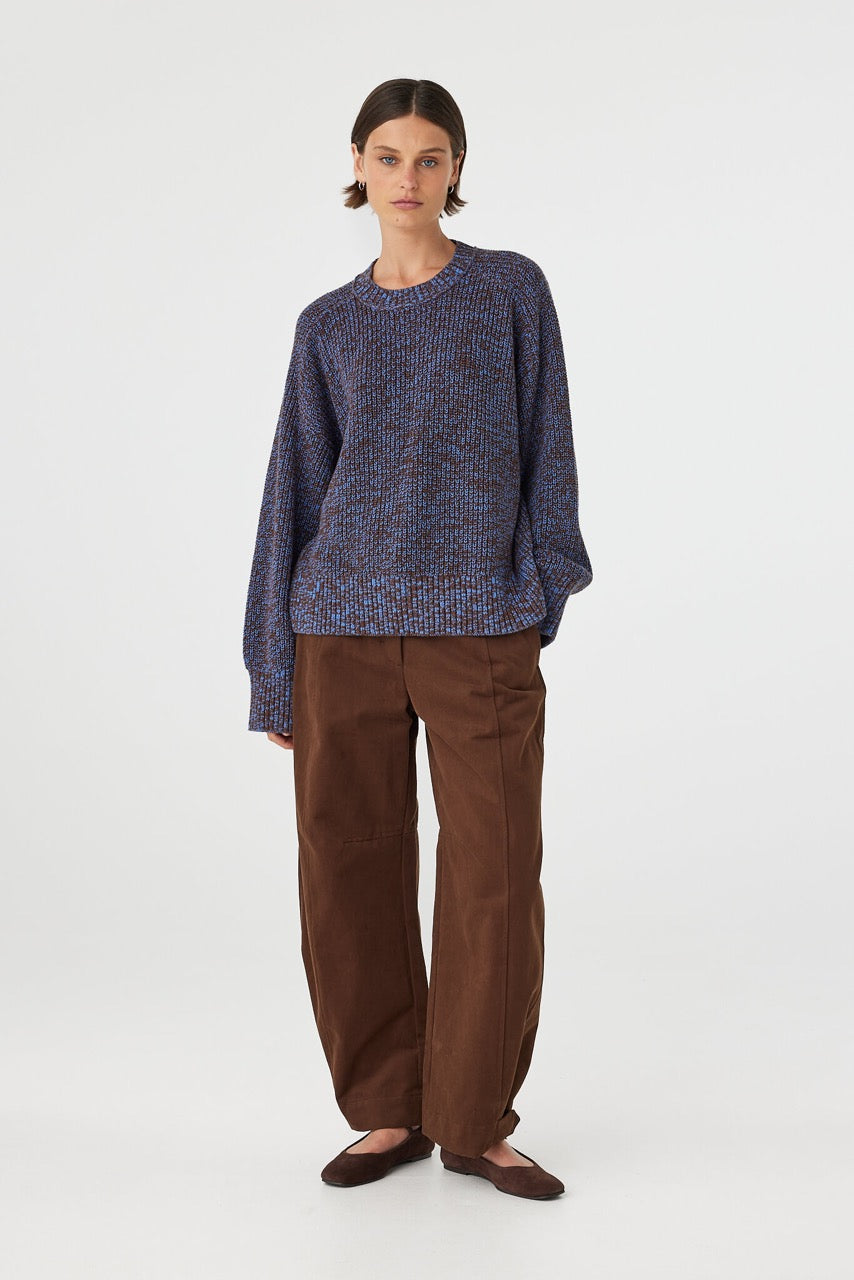 Solene sweater in chocolate and royal blue mottled cotton knit worn front on, featuring an oversized fit, raglan sleeves and ribbed neckline, styled with brown pants and flats
