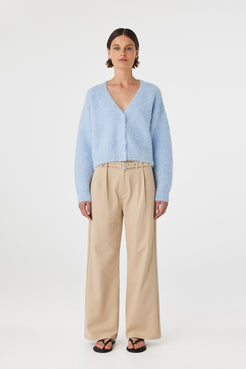 Liora fluffy cardigan in sky worn front on, featuring a button-up front, cropped length and relaxed silhouette, styled with beige trousers and black sandals