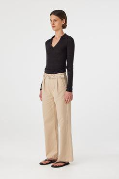 Mae longsleeve top in black shown in side profile, highlighting the fitted shape, long sleeves and lightweight knit finish, styled with beige pants and sandals