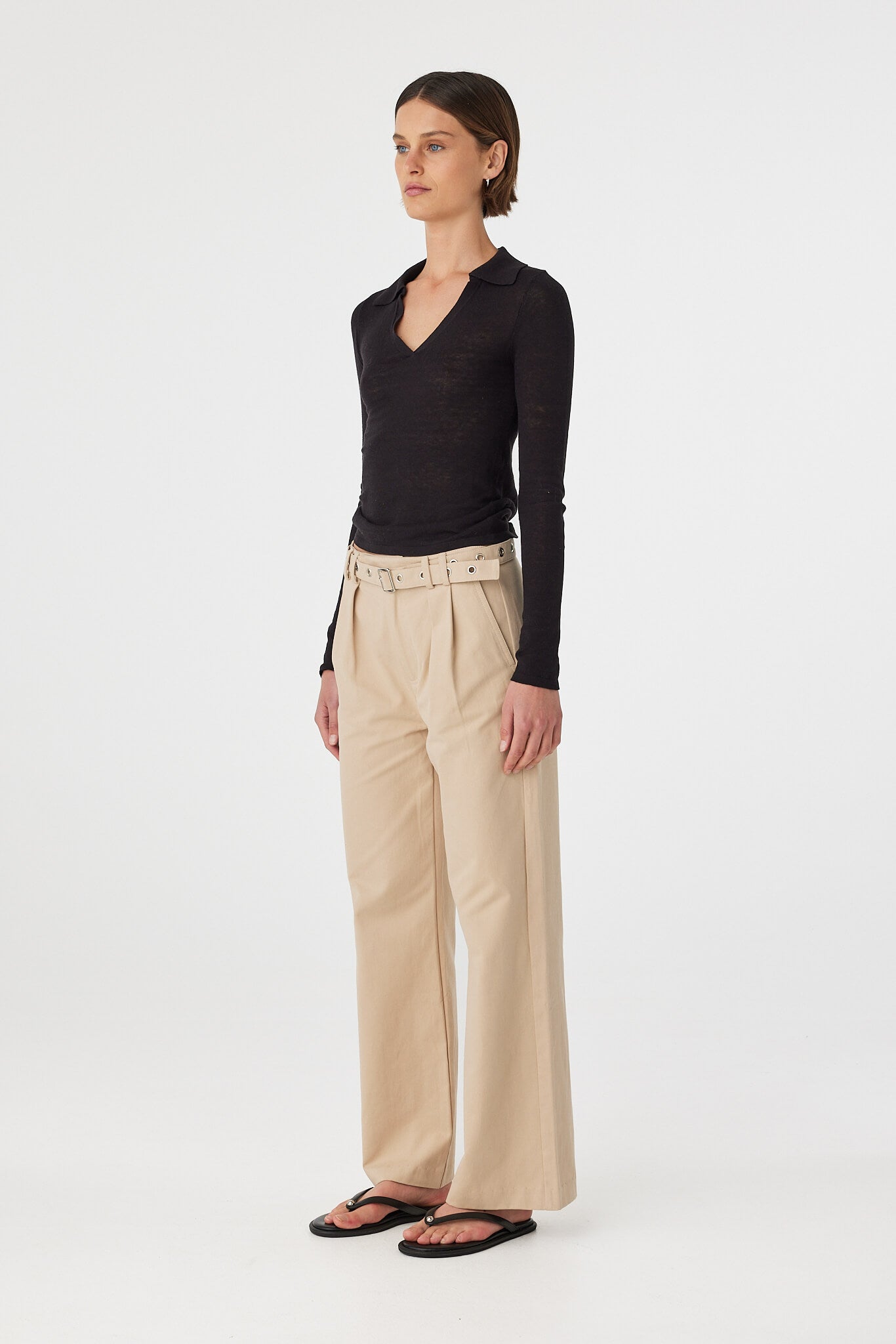 Soraya Pant taupe angled front view showing pleat detail and wide leg silhouette with eyelet belt styled with black fitted top