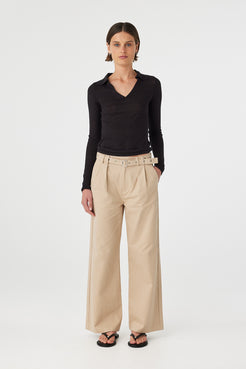 Mae longsleeve top in black worn front on, showing the soft drape, V neckline and collar detail, styled with beige wide-leg pants and sandals