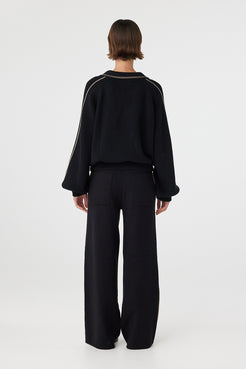 Nella zip sweater in black and taupe viewed from back, featuring the relaxed silhouette, ribbed waistband and subtle piping detail along the shoulders and sleeves