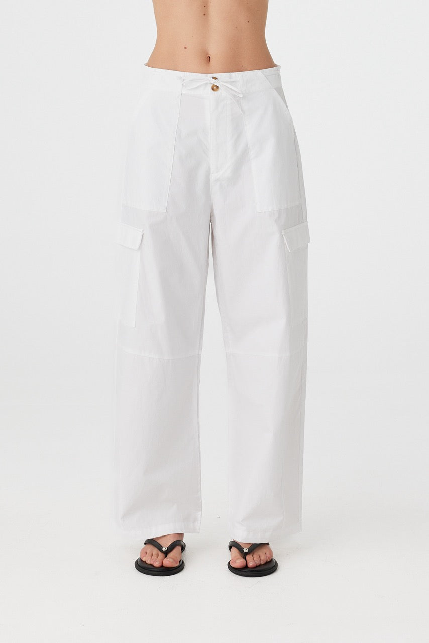 Close-up of 100% cotton pants with tie-and-button front closure, side patch pockets, and soft drape through the thigh.