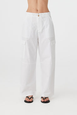 Close-up of 100% cotton pants with tie-and-button front closure, side patch pockets, and soft drape through the thigh.