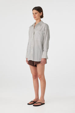 Side profile of woman in black and white striped oversized shirt