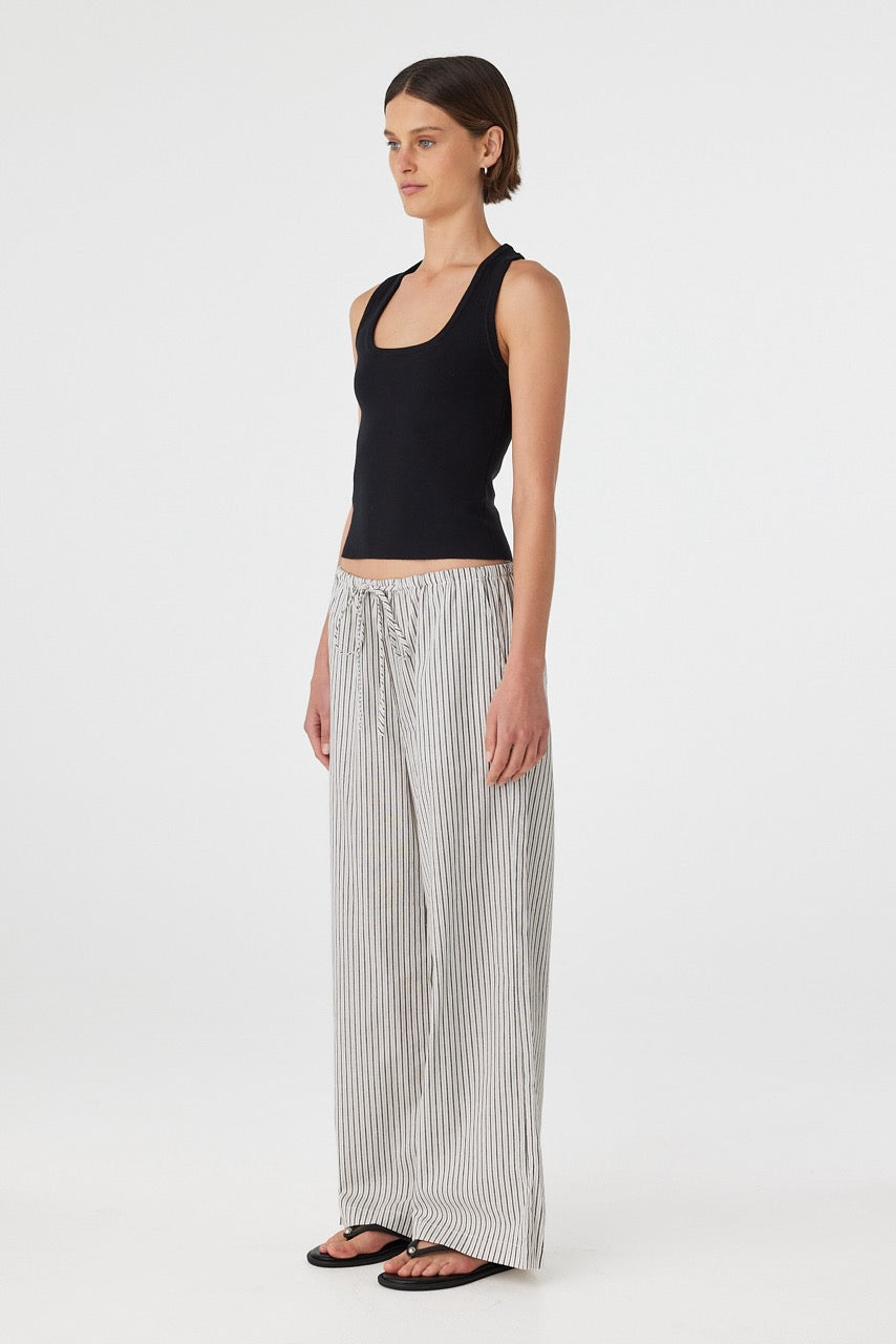 Three-quarter view of outfit with black tank and black white striped straight-leg pants