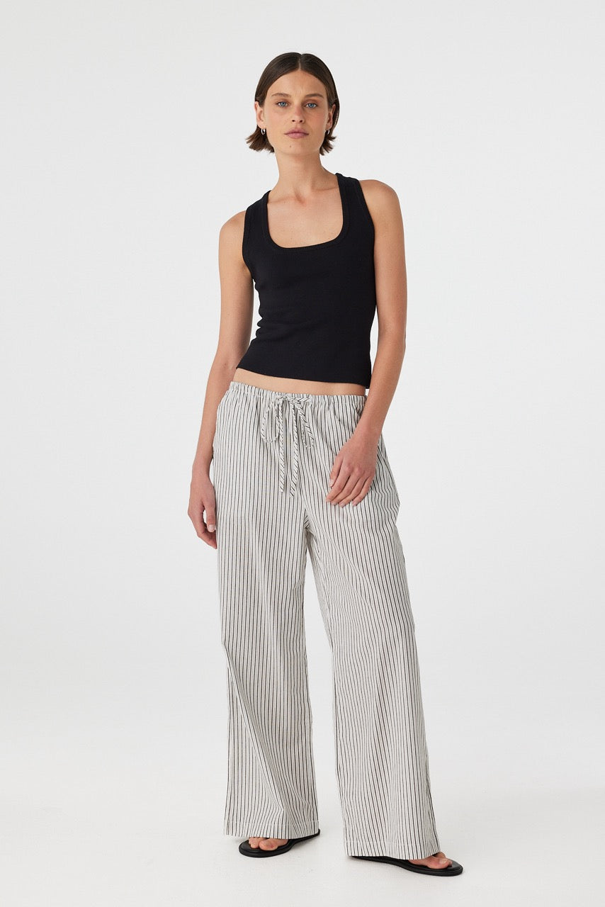 Front view of model wearing black and white striped straight-leg cotton pants with black tank