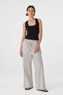 Front view of model wearing black and white striped straight-leg cotton pants with black tank