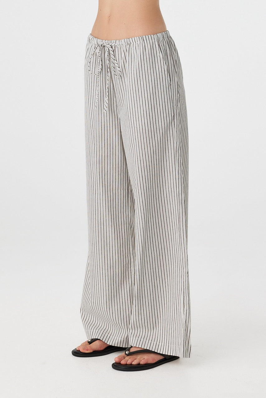 Side profile of woman in black and white striped straight-leg pants