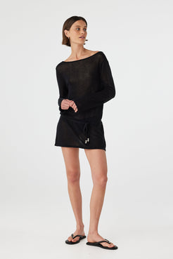 Model walking in a lightweight sheer cotton long sleeve mini dress in black, highlighting relaxed movement and off-body fit for beach to café wear.