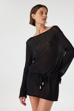 Sheer black cotton mini dress with long sleeves and removable waist tie, styled loosely to show adjustable shape and relaxed coastal layering.