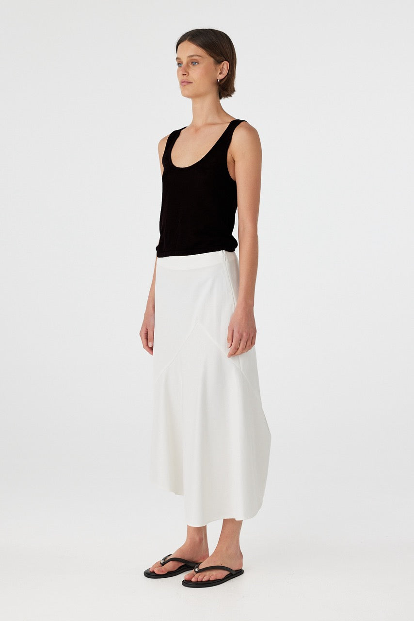 Black cotton semi-sheer tank with scoop neckline and low-back detail, styled with white wide-leg pants.