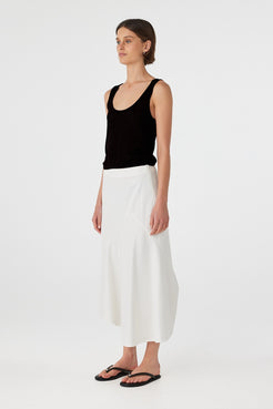 Black cotton semi-sheer tank with scoop neckline and low-back detail, styled with white wide-leg pants.