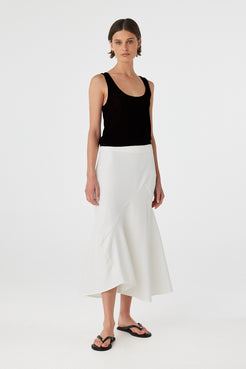 Model wearing a black cotton knit tank top paired with an asymmetrical white skirt, showcasing the relaxed fit, low-back detail, and soft movement of natural cotton layers.