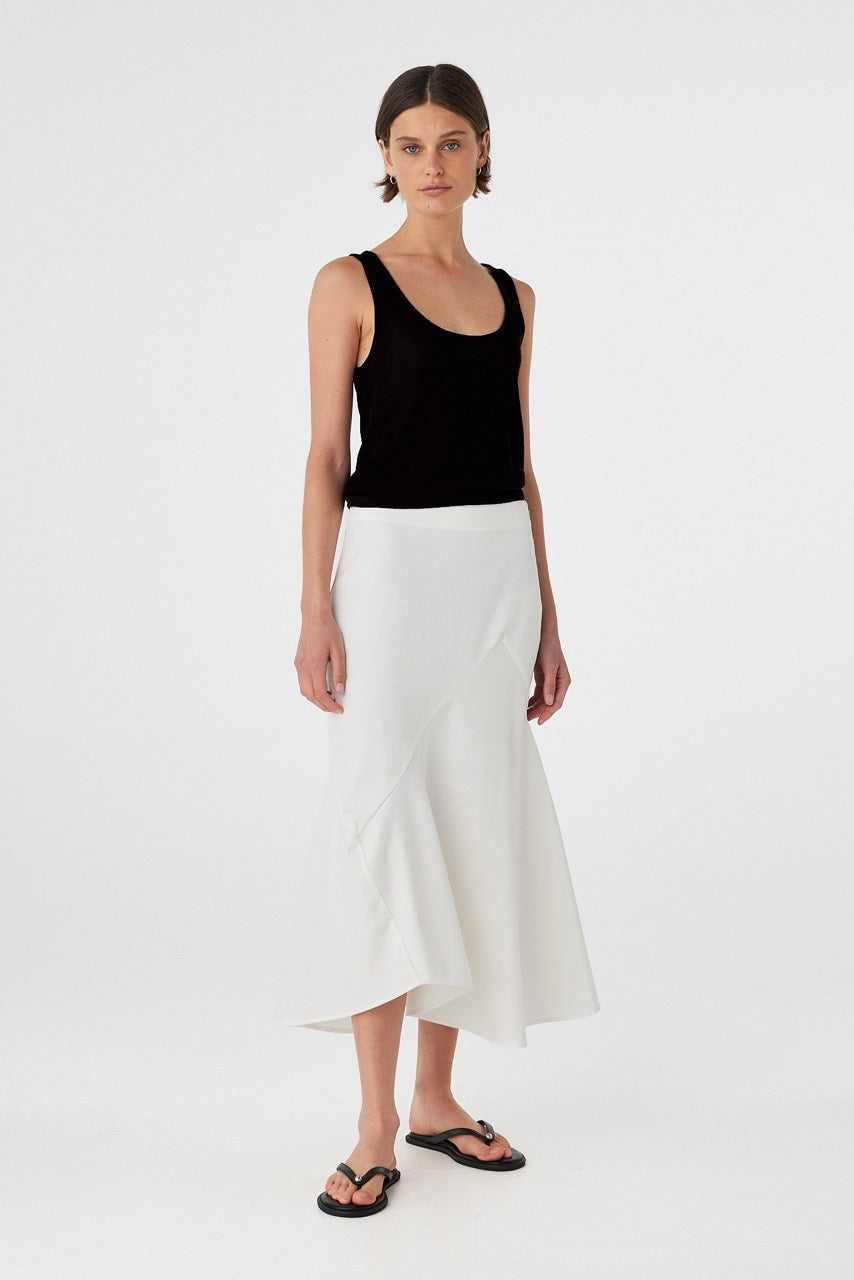 Model wearing a black cotton knit tank top paired with an asymmetrical white skirt, showcasing the relaxed fit, low-back detail, and soft movement of natural cotton layers.