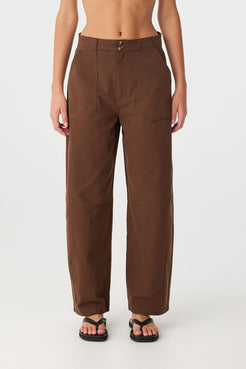 Close-up of chocolate barrel-leg cotton pants with darted legs and front patch pockets.